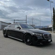 a black mercedes s - class is parked on the street in front of some power lines