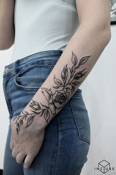 a woman's arm with flowers and leaves tattooed on the left side of her arm