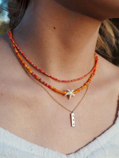 a woman wearing an orange beaded necklace with a starfish charm on it's neck