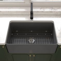 a black kitchen sink sitting under a window next to a green cabinet and counter top