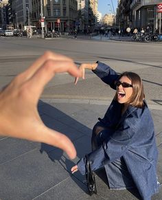 a woman sitting on the ground pointing at someone's hand in the middle of the street