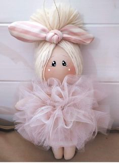 a doll with blonde hair wearing a pink tutu and a bow on her head