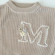 a knitted sweater with the word love written in white letters and flowers on it
