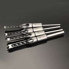 five wrenches sitting on top of each other in the middle of a table with black background