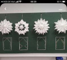 paper snowflakes are hanging on a green board