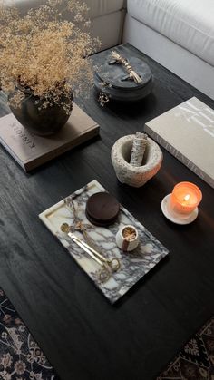 a black table topped with a vase filled with flowers next to candles and other items