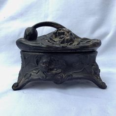 an old black metal box on a white cloth covered tablecloth with a skull in the center