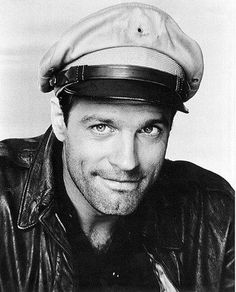 a black and white photo of a man wearing a leather jacket with a hat on his head
