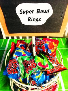 a basket filled with candy sitting on top of a green floor next to a sign that says super bowl rings