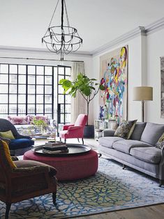 a living room filled with furniture and a painting on the wall above it's windows