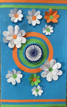 an art project made with paper flowers on a blue background and orange, white, and green circles