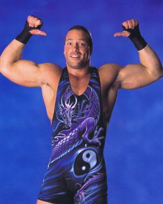 a man in a wrestling suit with his arms up and one hand raised above his head