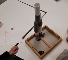 two people sitting at a table working on an object that looks like a rocket ship