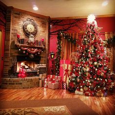 a decorated christmas tree in a living room with red walls and wooden floors, surrounded by presents