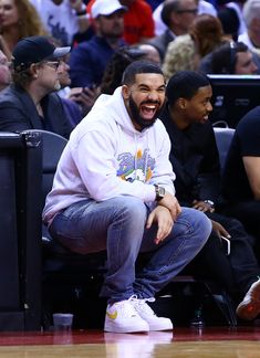 a man sitting next to another man on top of a basketball court in front of a crowd