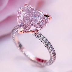 a pink diamond ring sitting on top of a flower