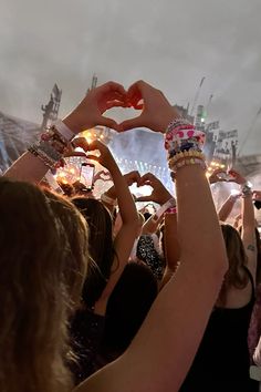 a group of people holding their hands in the shape of a heart at a concert