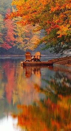 two chairs sitting on top of a wooden boat in the middle of a body of water