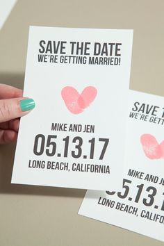 two save the date cards with pink hearts on them are being held by a woman's hand