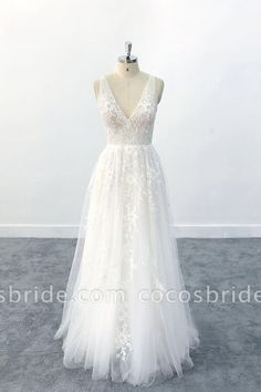 a white wedding dress on a mannequin stand in front of a white wall