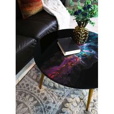 a coffee table with a book on it in front of a black leather couch and chair
