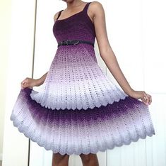 a woman in a purple and white crochet dress is holding her hand on her hip