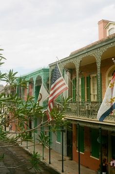 the american and mexican flags are hanging on the balcony of an old building in new orleans