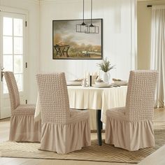 a dining room table with four chairs and a white table cloth on top of it