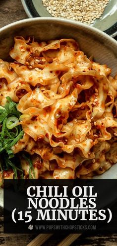 a bowl filled with noodles and greens on top of a wooden table