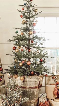 a small christmas tree sitting in a bucket next to presents and other holiday decor items