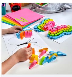 a person is cutting out letters from construction paper with scissors and colored glue on a table