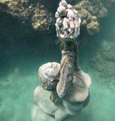 a person is sitting on top of a rock in the water with their hands up