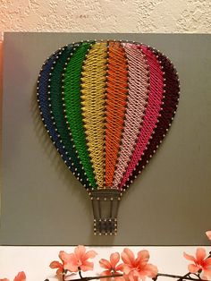 a colorful hot air balloon is hanging on the wall next to pink flowers and branches