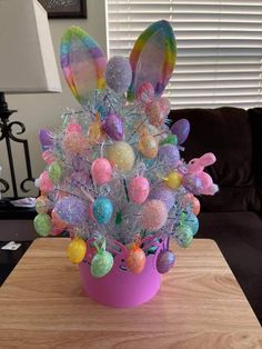 a pink vase filled with easter eggs on top of a wooden table