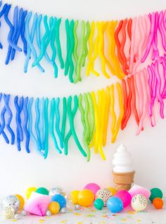 an ice cream cone and rainbow streamers on a white wall