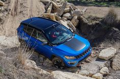 a blue jeep driving up a rocky hill