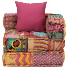 a colorful couch with pillows stacked on top of each other and one pink pillow in the middle