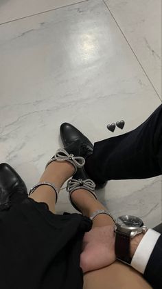 two people sitting on the ground with their feet in each other's lap and one person wearing black shoes