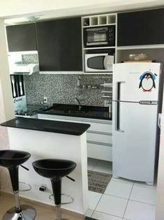 two stools are in front of the kitchen counter and refrigerator, which is decorated with penguin decals