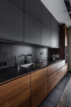 a kitchen with wooden cabinets and black counter tops, along with a stainless steel sink