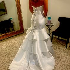 a woman in a wedding dress looking at herself in the mirror with her back to the camera