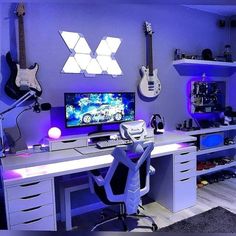 a computer desk with a guitar on it in front of a purple wall and blue lighting