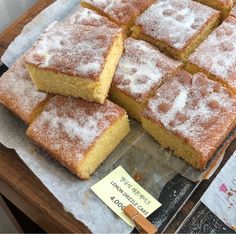 several pieces of cake sitting on top of a wooden cutting board next to a sign