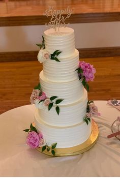 a white wedding cake with pink flowers on the side and a happy birthday topper