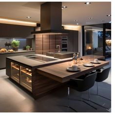 a modern kitchen with an island countertop and dining room table in the center, lighted by recessed lighting