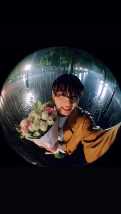 a man is holding flowers in a glass ball