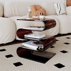 a coffee table with magazines on it in front of a white couch and black and white rug