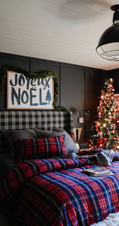 a bedroom decorated for christmas with a tree and plaid bedding