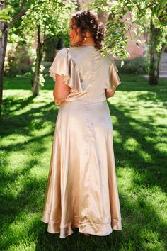 a woman in a dress standing under a tree