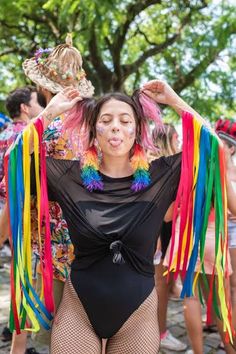 a woman in a bodysuit with colorful streamers around her neck and hands behind her head